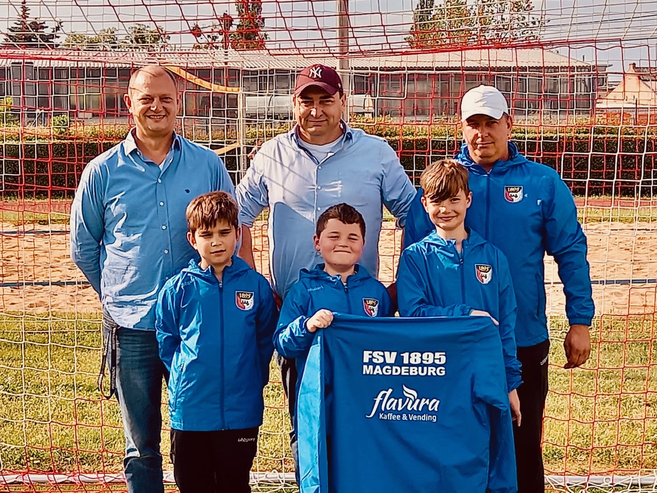 Kristian Klatt (l.) und Holger Ballwanz (M.) von Flavura überreichen die neuen Regenjacken für die E-Jugend des FSV 1895 Magdeburg. Foto: Flavura